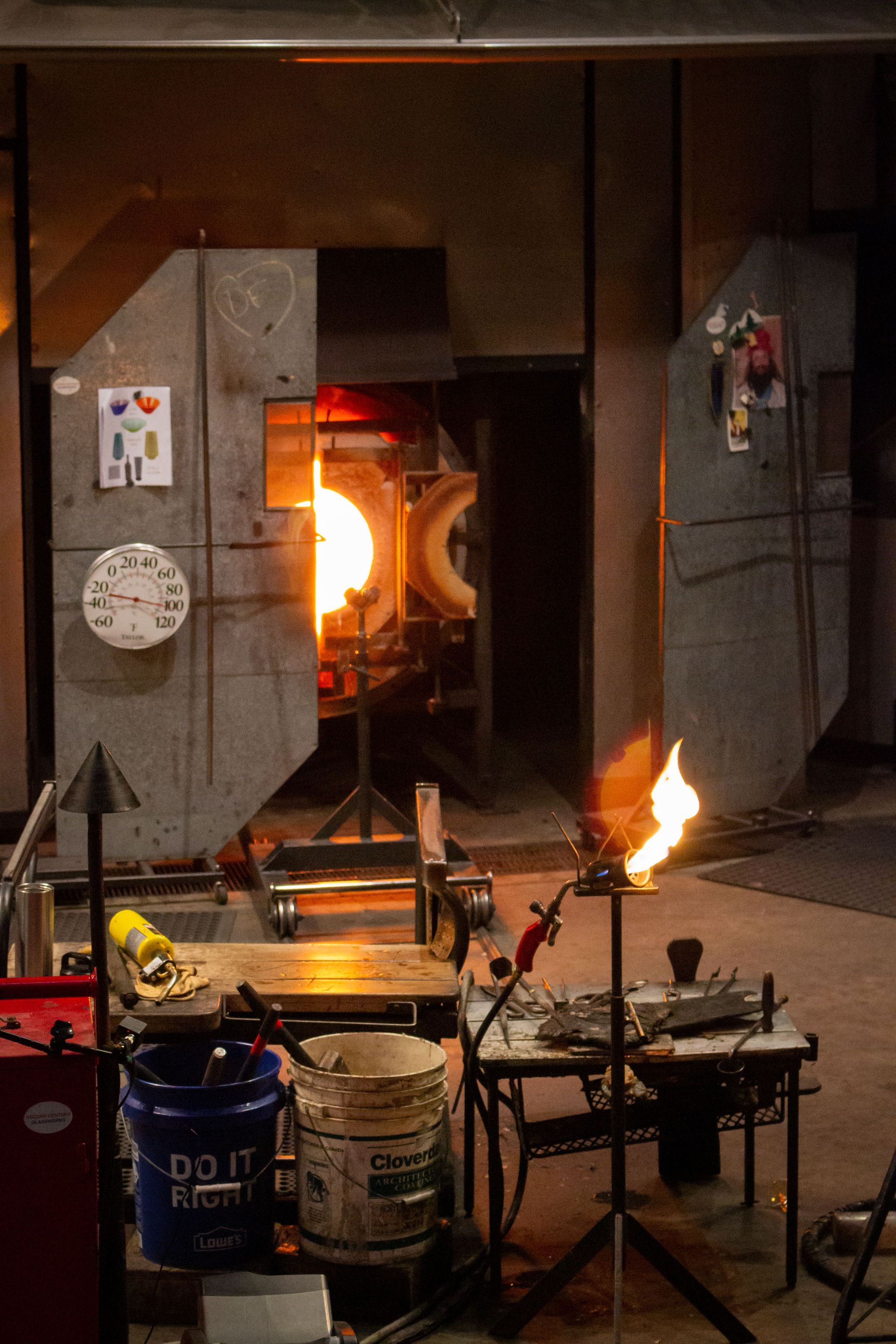 Artisan glass blowing workshop featuring a glowing furnace and tools in a creative environment.